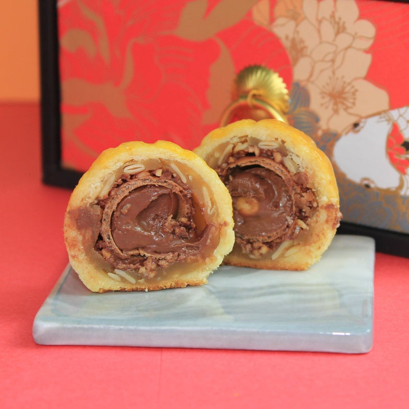 Shanghai Mooncake filled with a whole Rocher. Wrapped around with white lotus paste filling with melon seeds. 
